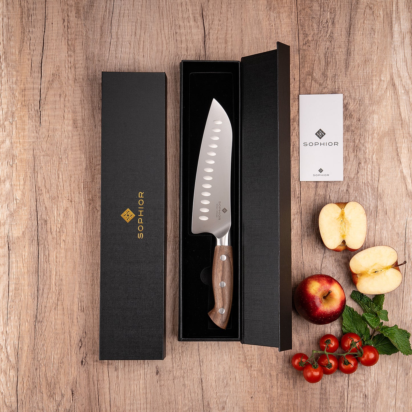 Santoku 19 cm in zwarte geschenkverpakking op houten ondergrond met appel en tomaten