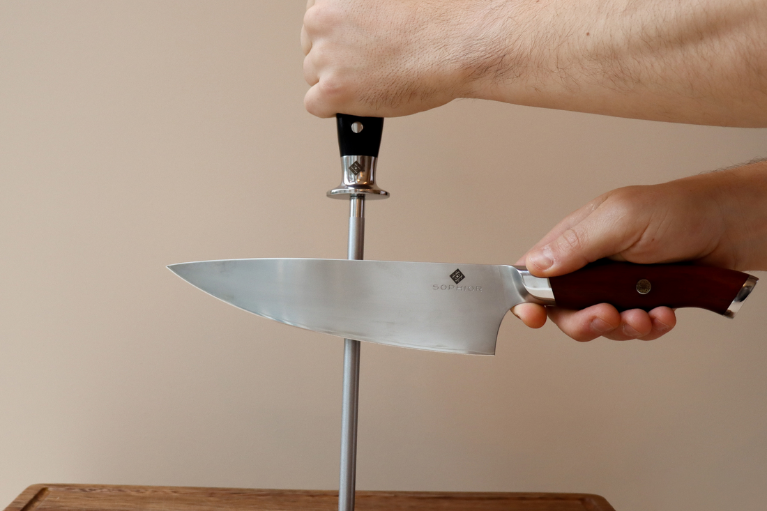 Handen slijpen koksmes met diamant slijpstaaf op houten snijplank tegen lichte achtergrond