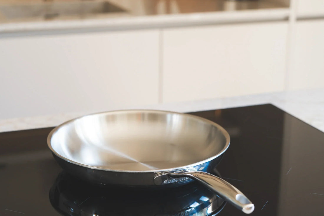 RVS koekenpan met SOPHIOR-logo op zwarte inductiekookplaat in moderne lichte keuken