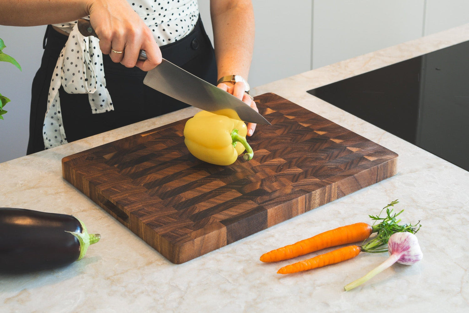 SOPHIOR bestseller snijplank van walnoot met gele paprika wordt gesneden in moderne keuken
