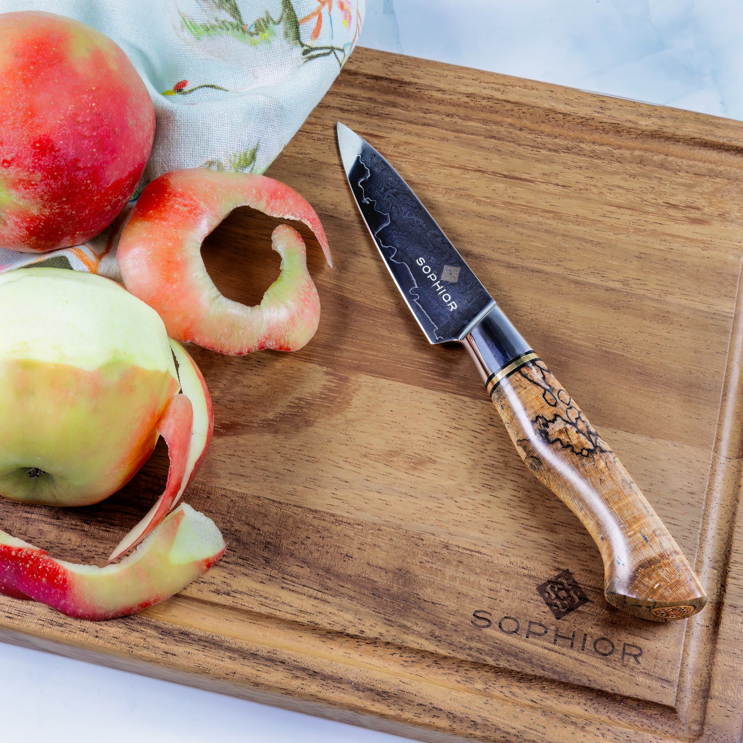 SOPHIOR Schilmes - Elegance Collection op acacia snijplank naast geschilde appels