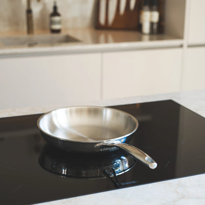 RVS koekenpan Ø24 cm staand op inductiekookplaat in lichte keukensetting