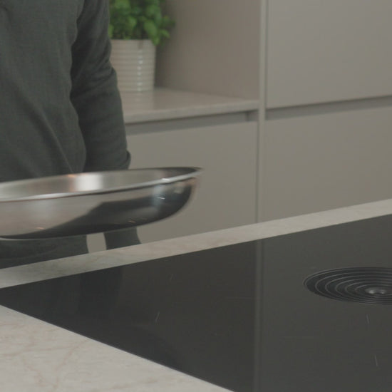 Productvideo: RVS koekenpan 28 cm wordt boven inductiekookplaat gehouden in moderne keuken