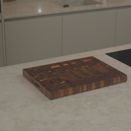 Productvideo: acacia kopshout snijplank 40x30x3,5 cm op een licht keukenblad naast inductiekookplaat