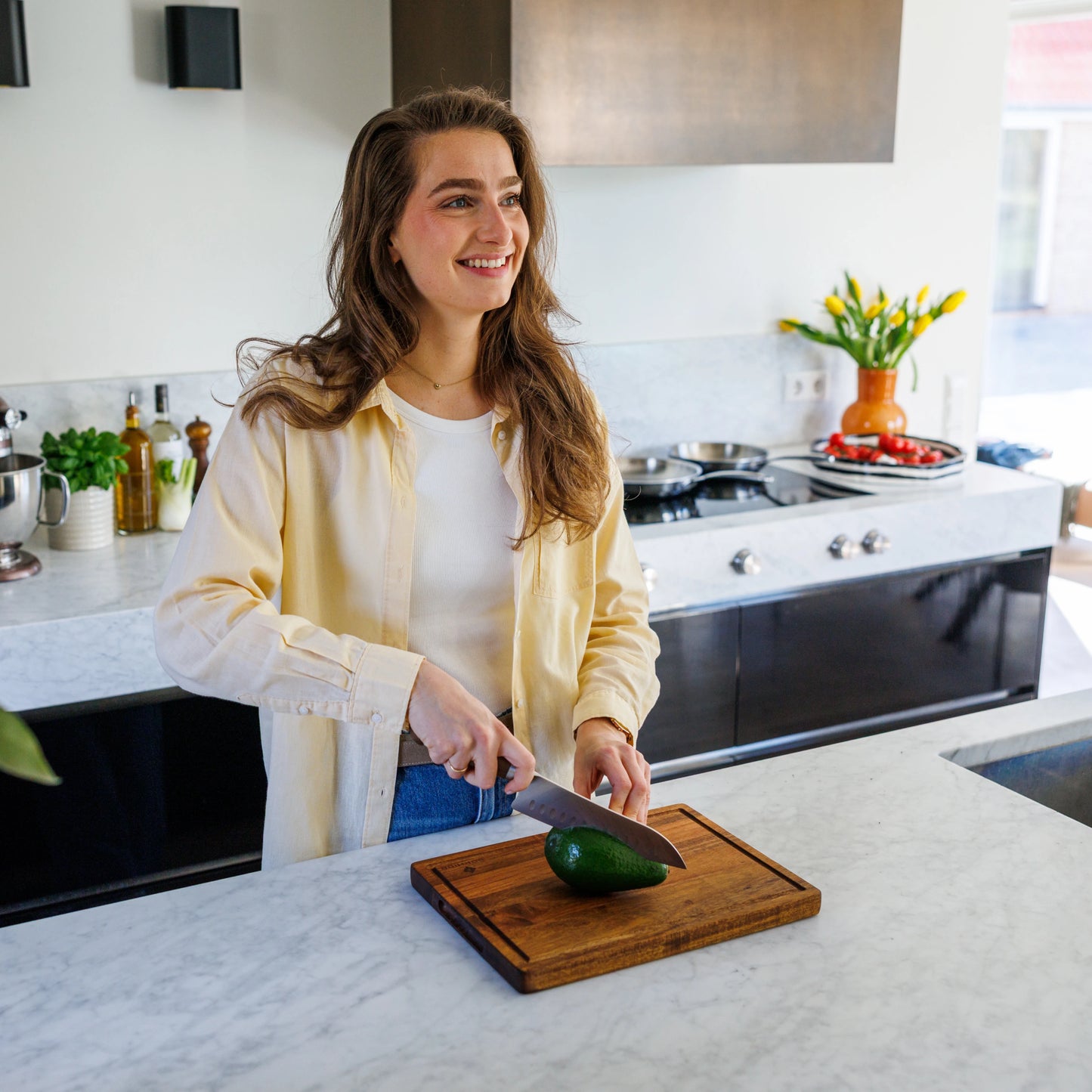 Houten Snijplank Acacia – 35×25×2,5 cm in gebruik door lachende vrouw in moderne keuken