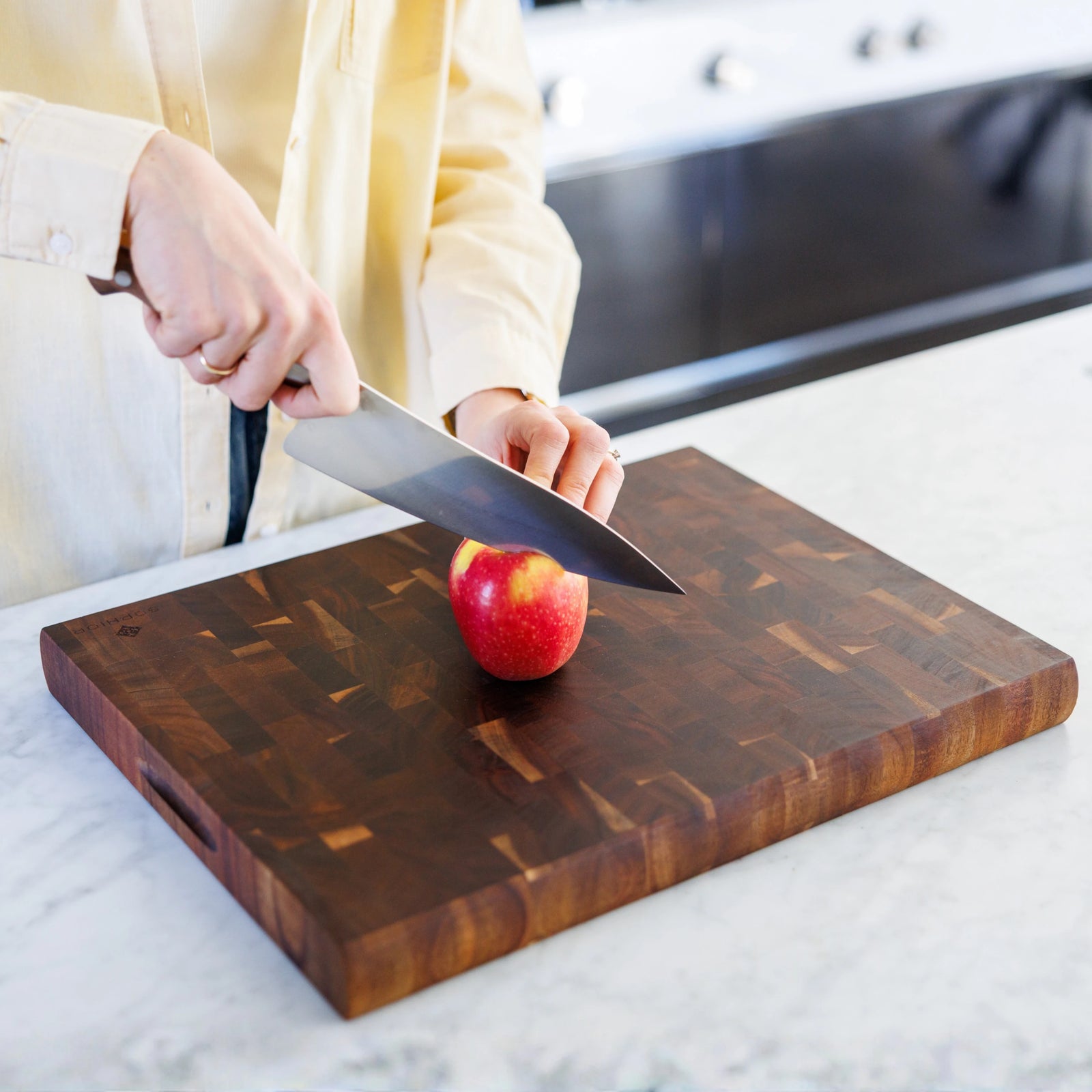 Houten Snijplank Acacia Kopshout – 45×35×4 cm in gebruik tijdens snijden van een appel op marmeren werkblad