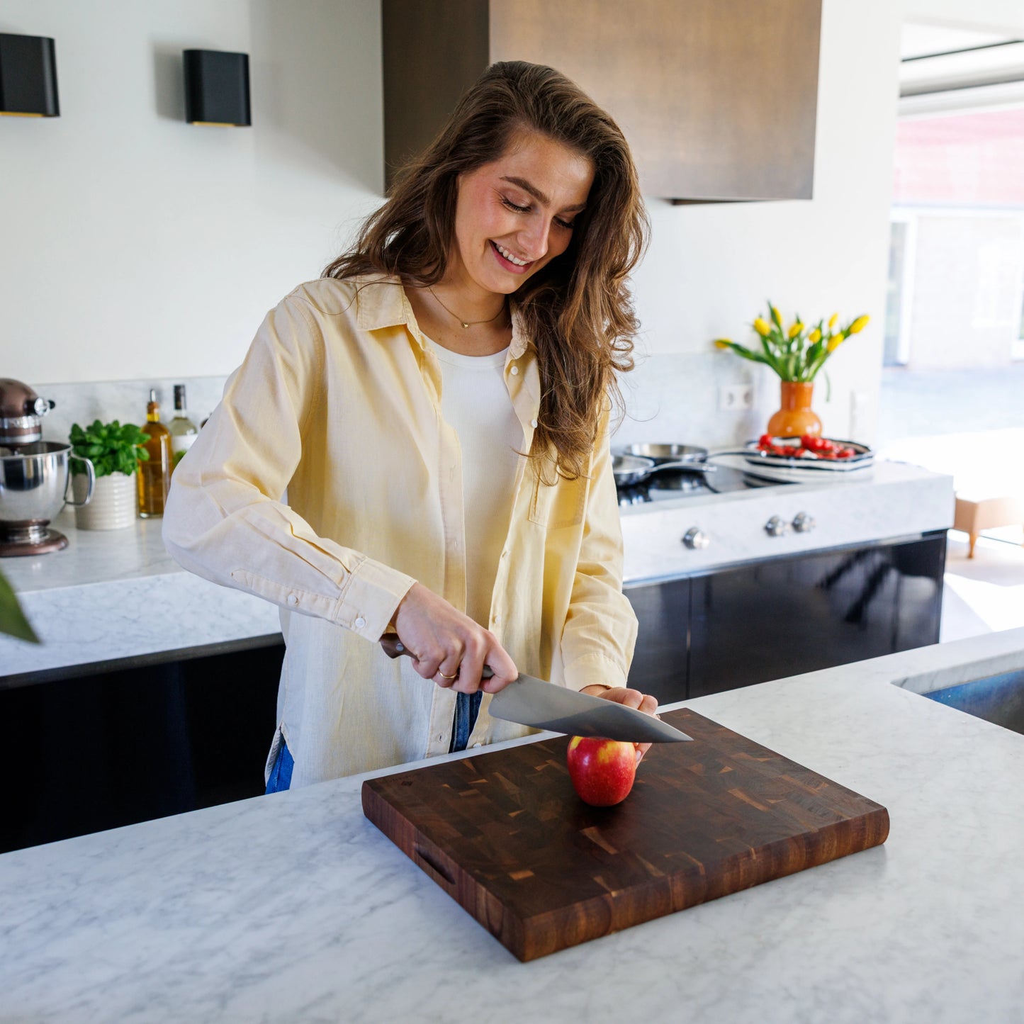 Houten Snijplank Acacia Kopshout – 45×35×4 cm in gebruik door lachende vrouw in moderne keuken