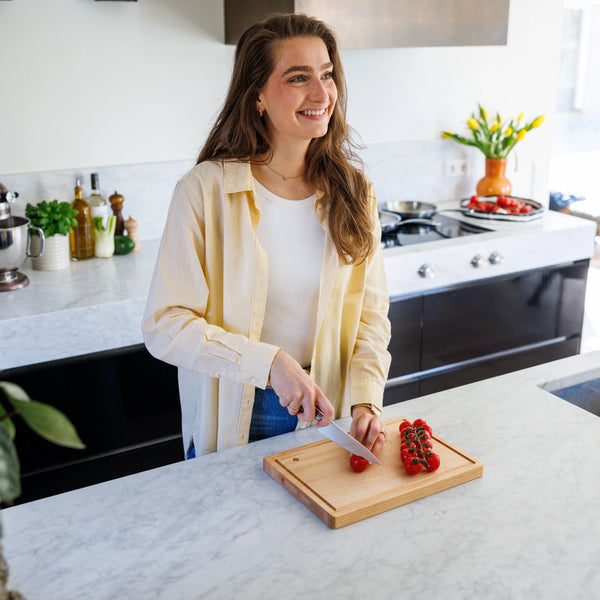 Houten Snijplank Esdoorn 35x25x2,5 cm in moderne keuken met vrouw die tomaten snijdt