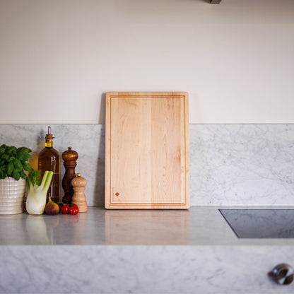 Houten Snijplank Esdoorn 42x30x2,5 cm staand op marmeren werkblad met venkel en kruiden