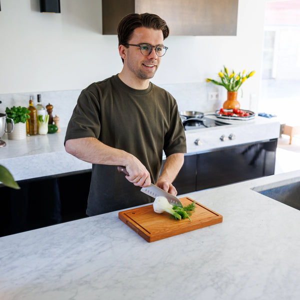 Houten Snijplank Kersen – 35×25×2,5 cm in gebruik door lachende man in moderne keuken