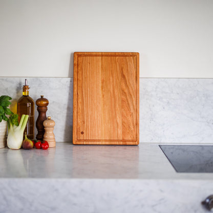 Houten Snijplank Kersen – 42×30×2,5 cm rechtop in keukensetting naast olie en peper
